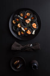 Noir Signature: Shrimp Pasta. Al dente pasta in rich squid ink sauce, paired with juicy shrimp, roasted cherry tomatoes, and fresh herbs for a bold, indulgent dish. (₩20,000)